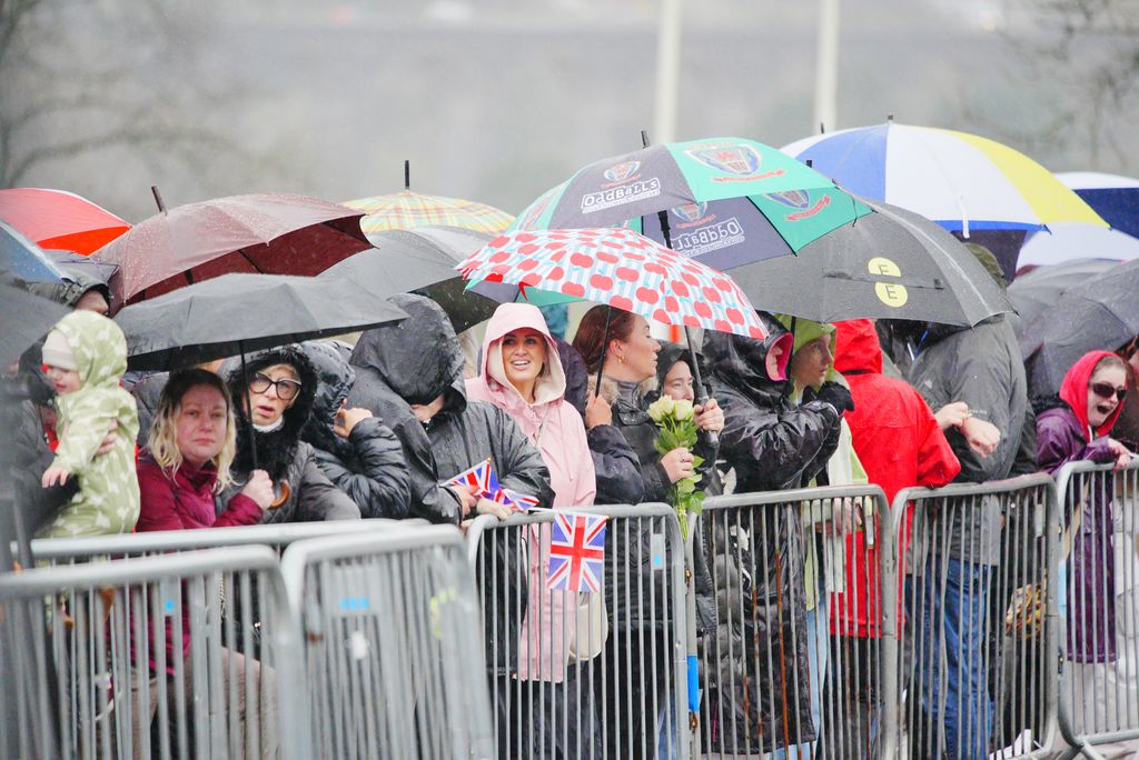 Members of the public wait in the rain ahead of the arrival of King Charles III and Queen Camilla for a visit to Cyfarthfa Castle in Merthyr Tydfil, South Wales, for a celebratory reception marking the Castle's 200th anniversary and the King's 77th birthday