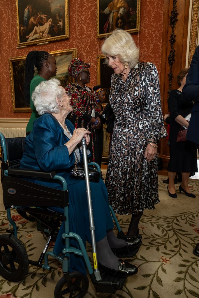 Queen Camilla speaking to lady in chair