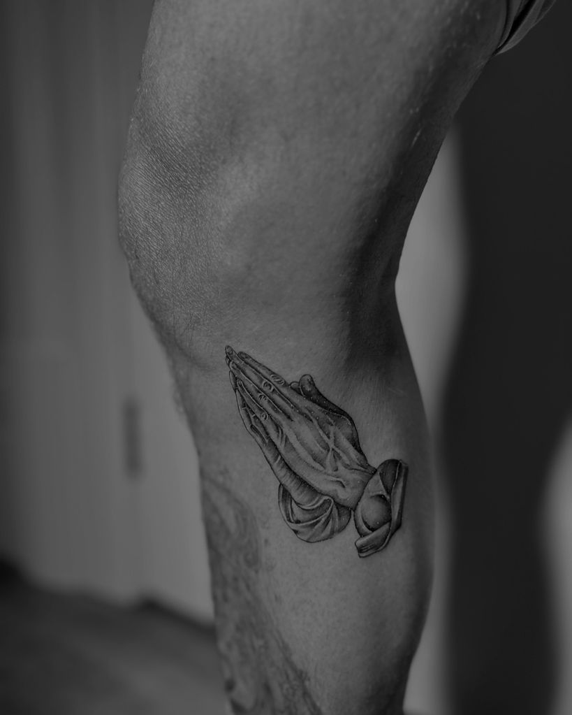 tattoo of praying hands on knee