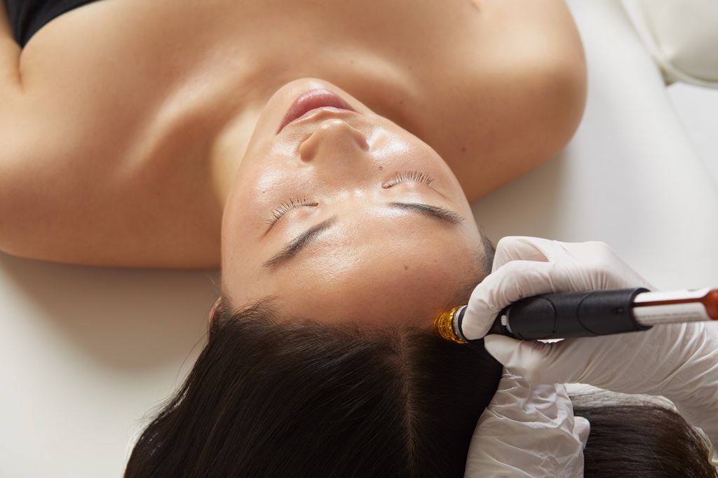 Woman lying on bed getting Keravive Hydrafacial treatment 