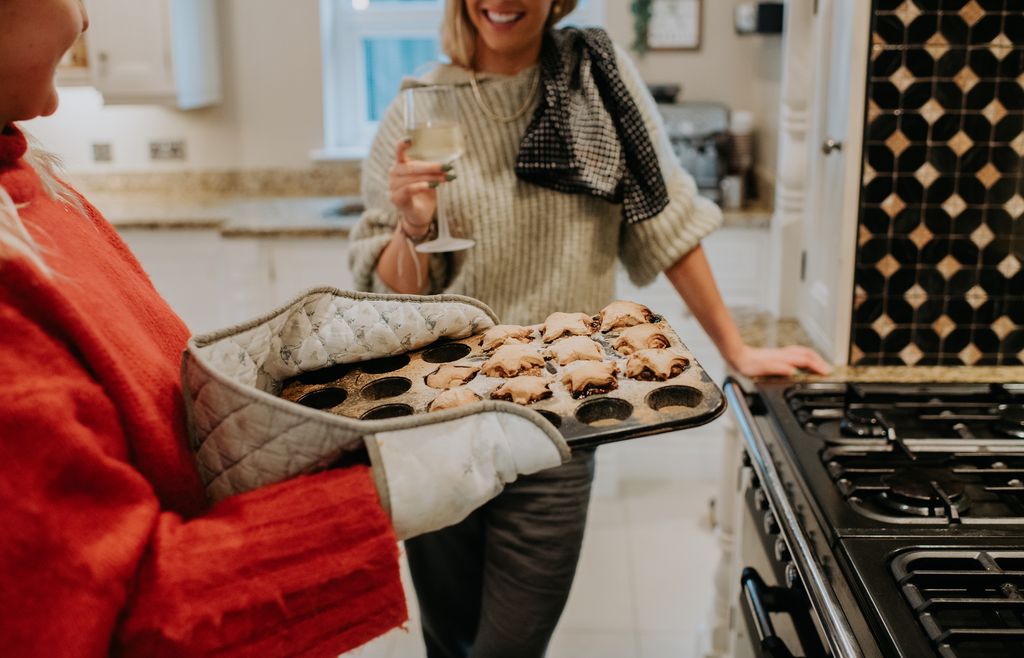 A woman removes freshly baked home made mince pies from an oven