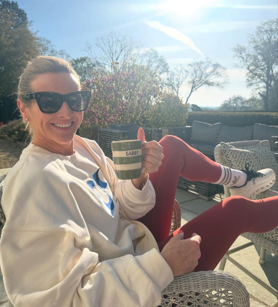 Gabby Logan putting her thumbs up in the sun in her garden
