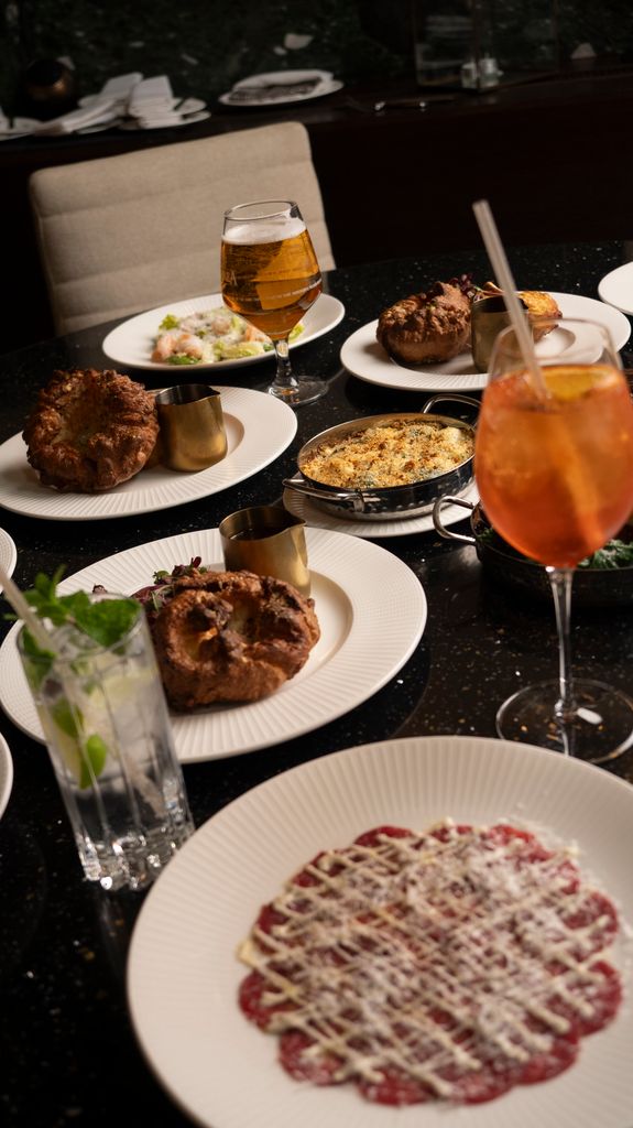 table with food on white plates and alcoholic drinks