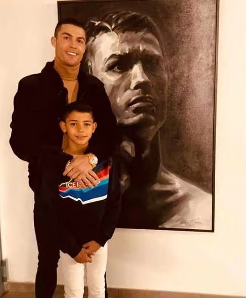 cristiano ronaldo stood in front of artwork of himself alongside son