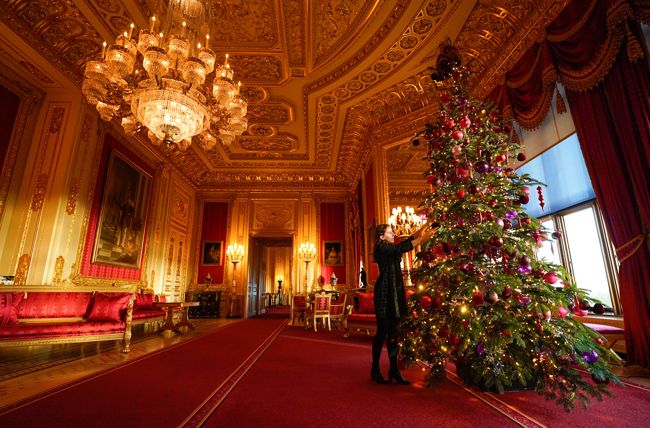 windsor castles christmas tree with staff member adding decorations