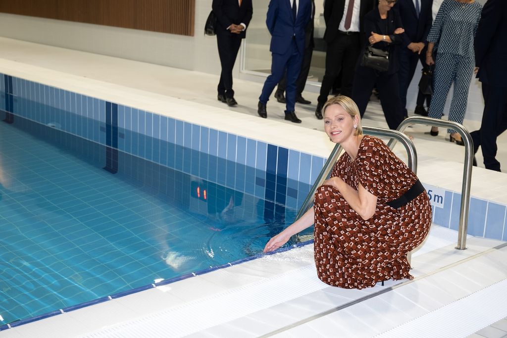 Charlene dipping hand in swimming pool