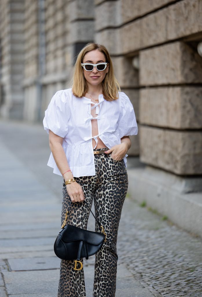   Sonia Lyson é vista vestindo bailarinas Zara, jeans com estampa de leopardo e blusa branca Ganni, bolsa e óculos de sol Dior, cinto Hermes em 01 de maio de 2024 em Berlim, Alemanha. 