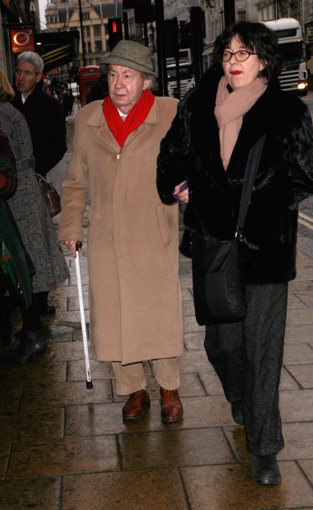 Peter Sallis using a walking stick walking with a woman