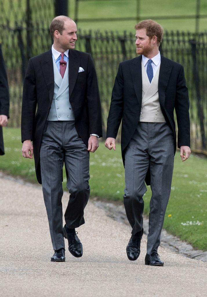 Prince Harry and Prince William looking at each other in morning suits