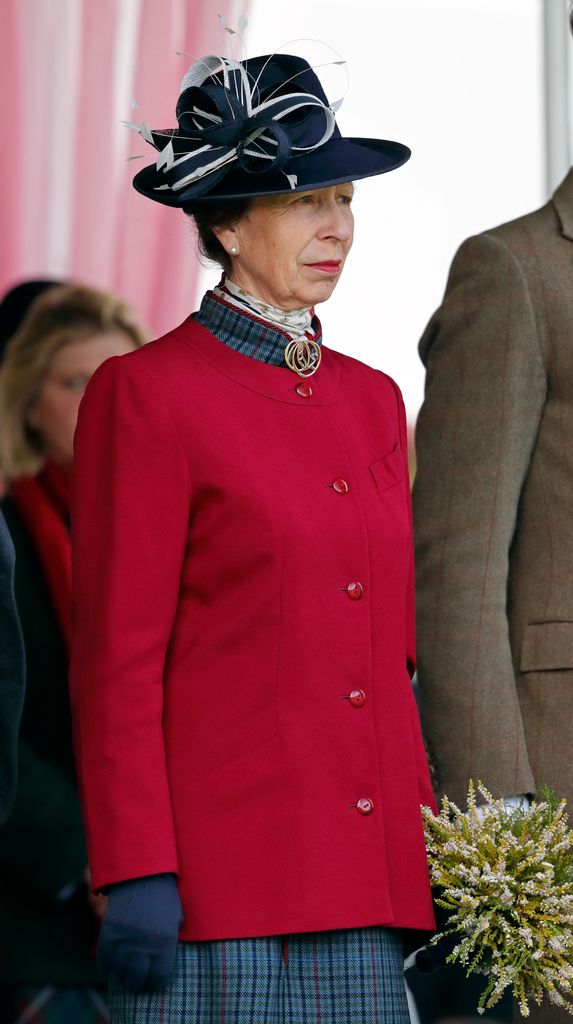 Princess Anne in red coat and blue accented hat