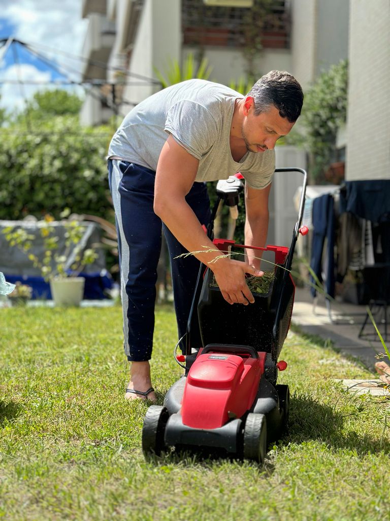 man with a lawn mower in back garden