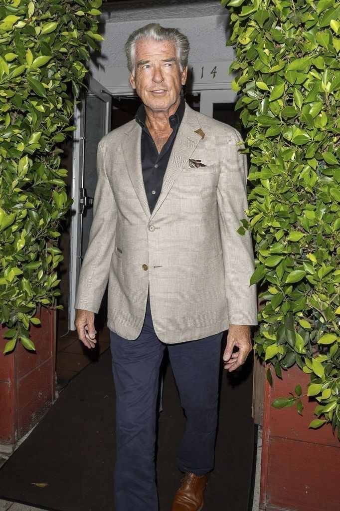  Pierce Brosnan in a cream blazer, black shirt, and navy pants