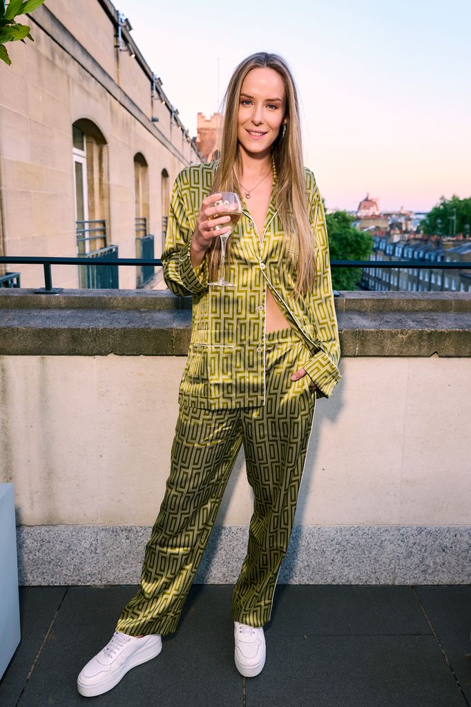 Hum Fleming brings retro energy in green geometric satin pyjamas, styled with white platform sneakers and sleek hair, while sipping Perrier-Jouët champagne on the rooftop of The Berkeley during golden hour.