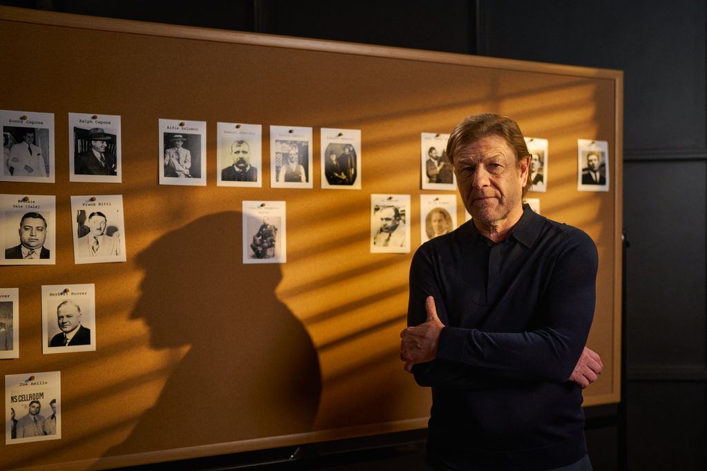 Sean Bean standing against pin board