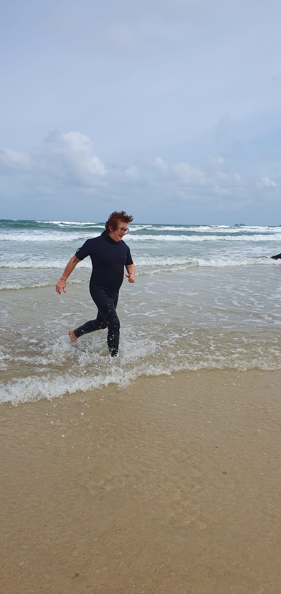 Woman dashing out of the sea in a wetsuit