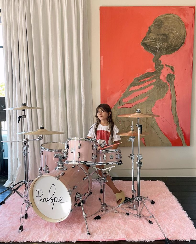 Penelope Disick playing drums on a fluffy pink carpet