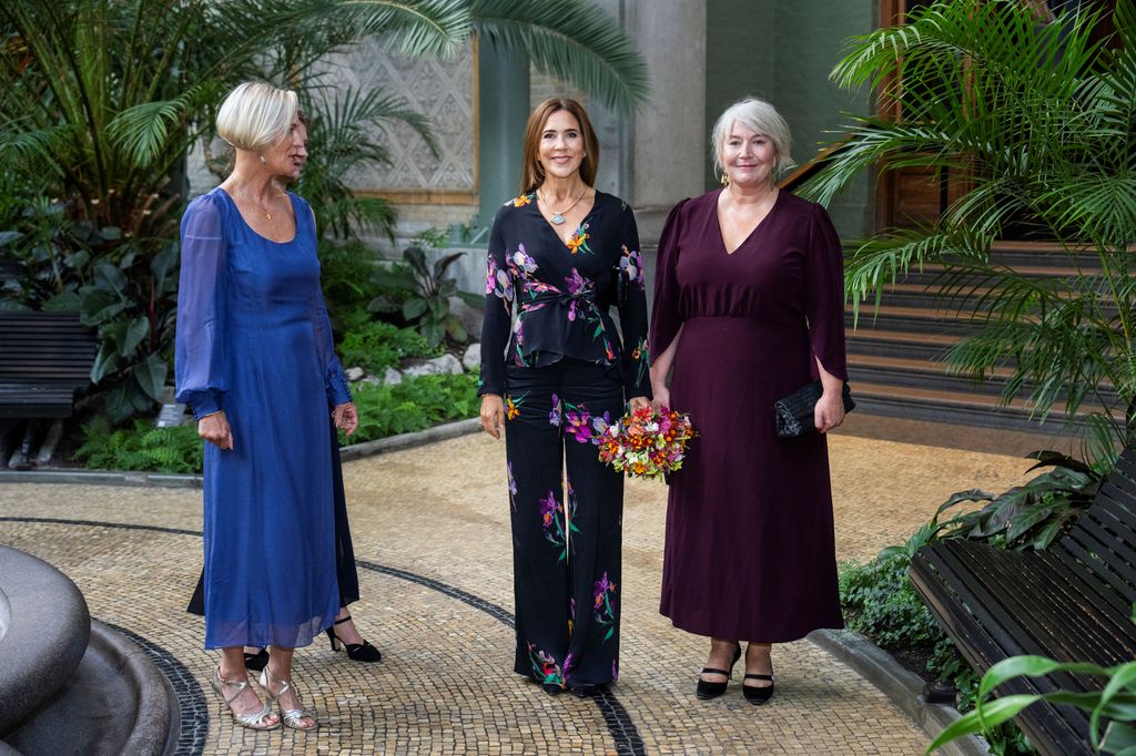 Queen Mary between two women outside