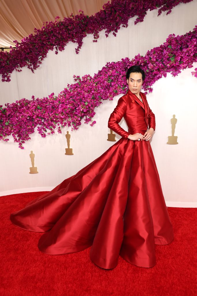 Eugene Lee Yang attends the 96th Annual Academy Awards wearing crimson red 