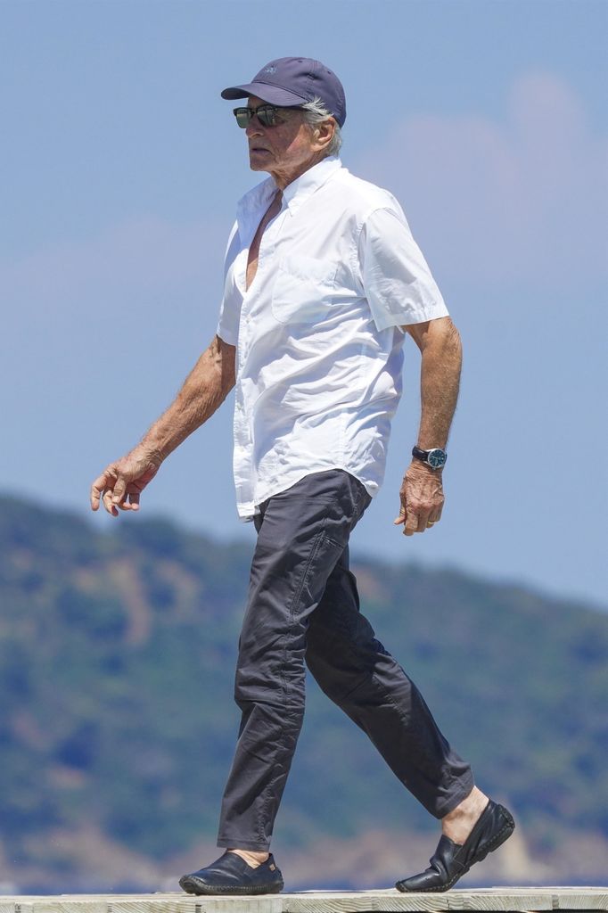 Michael walking jetty white shirt, baseball cap sun shining 