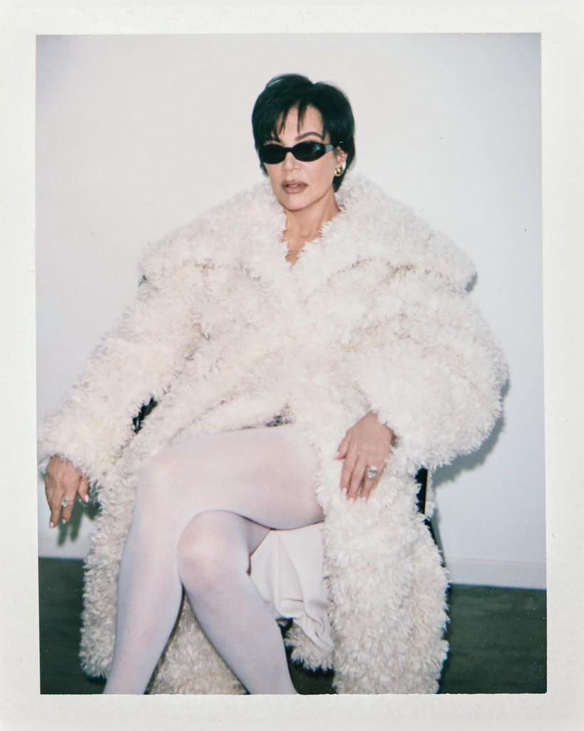 Kris Jenner sitting in a fluffy white coat and white tights for Kylie Jenner's khy fashion brand 