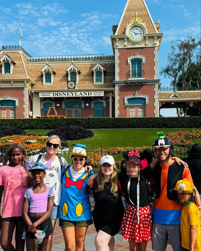 Charlize Theron (third from left) with her daughter Jackson (left) and August (second from left) and friends posing in front of the Disneyland Train Station