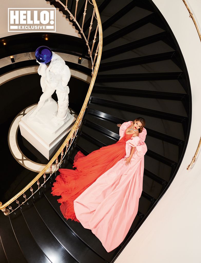 Natasha Poonawalla HELLO exclusive posing on black staircase at home in red dress with pink cape