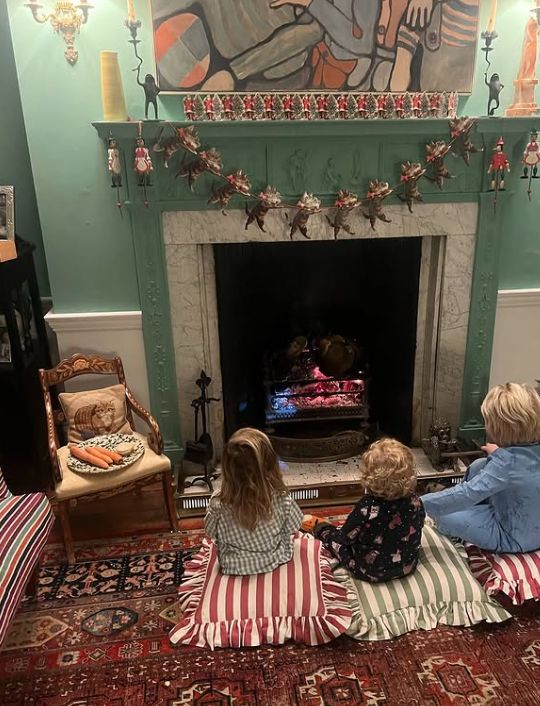 Three young children sat in front of a fireplace