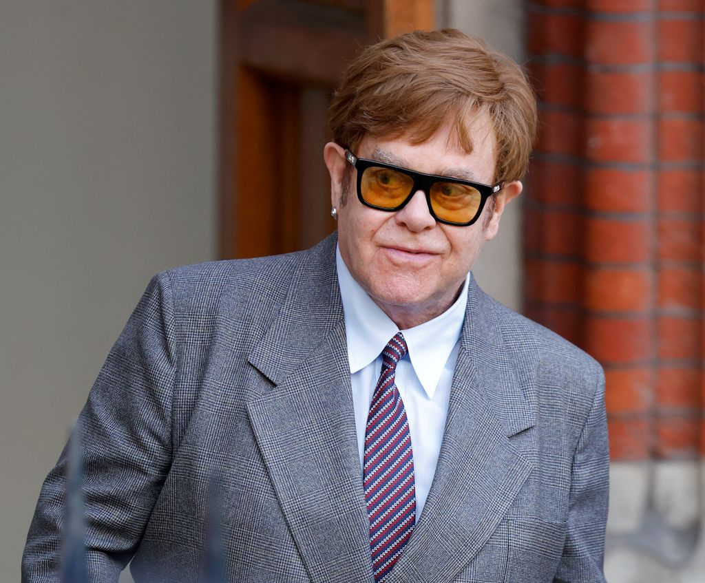 Elton John in a light grey suit