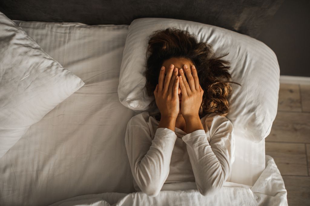 Tired woman in bed with hand over face