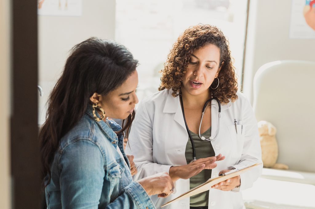 A female doctor discusses a young patient's diagnosis with the patient's mother. They are reviewing the patient's test resutls.