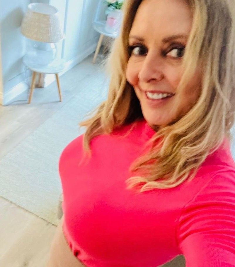 Carol Vorderman wearing a hot pink top and smiling