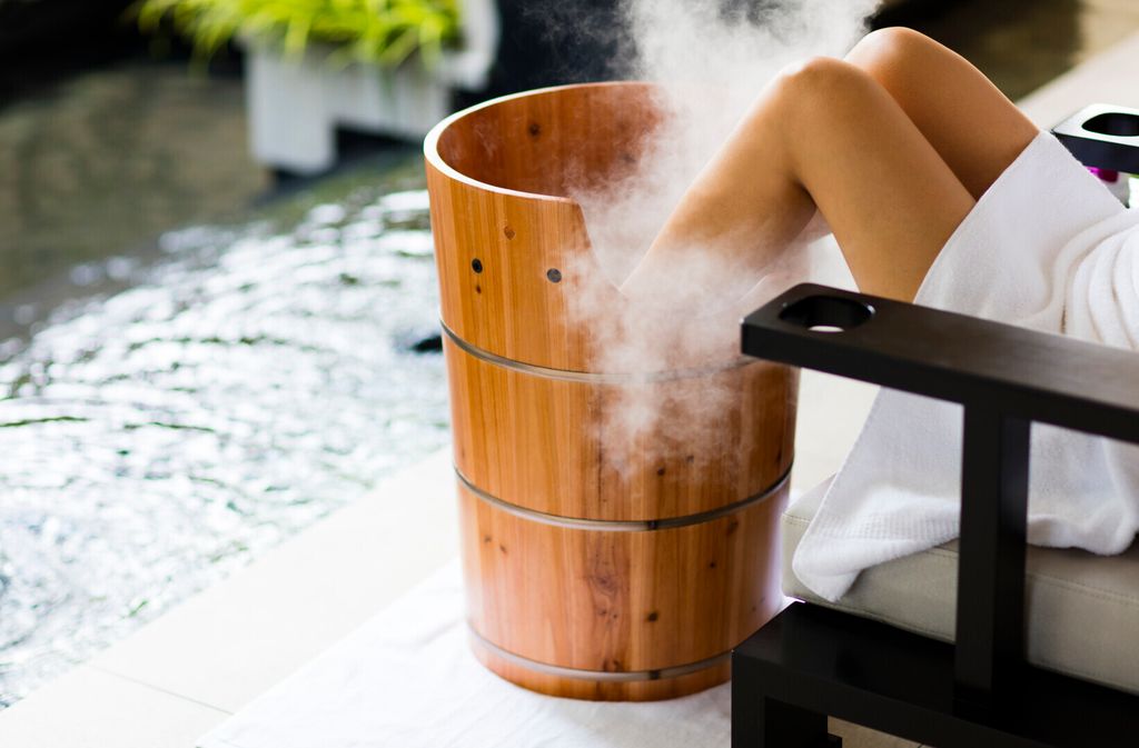 Woman sitting with feet in wooden foot spa - spa treatment at the Ritz-Carlton hotel Malaysia