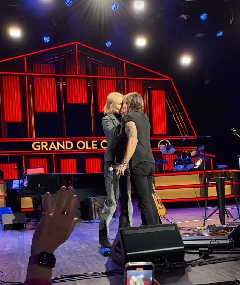 Still from a clip shared by the Grand Ole Opry Instagram of Nicole Kidman and Keith Urban sharing a kiss on stage, November 2024