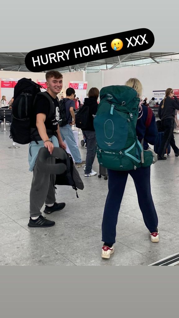 Two people walking through an airport with backpacks on