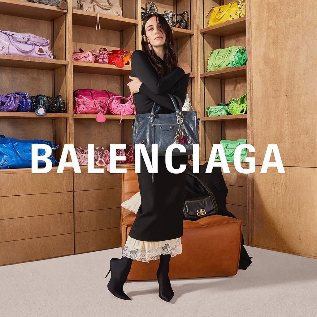 Devon Lee Carson poses in a closet for Balenciga's new campaign, wearing a black tight dress with cream lace trim