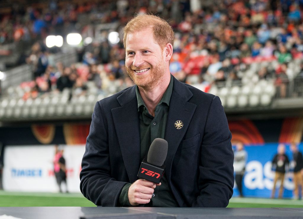 Prince Harry smiling in stadium holding mic