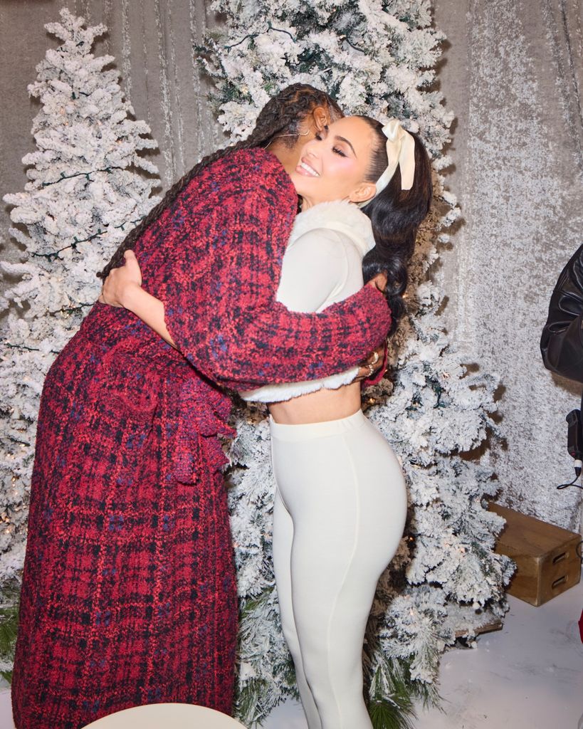 Kim Kardashian and Snoop Dogg hug in front of 2 Christmas trees covered in fake snow