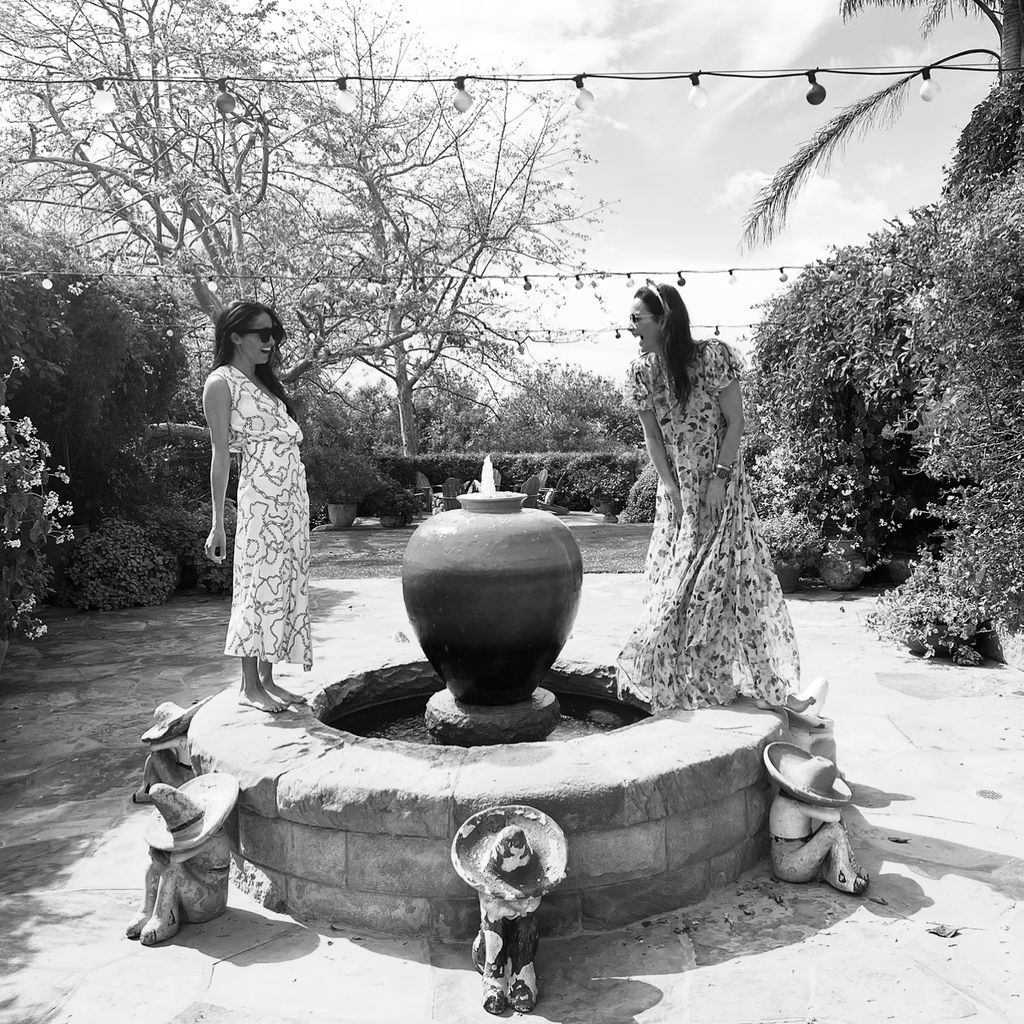Meghan and Kelly in black and white photo standing on fountain