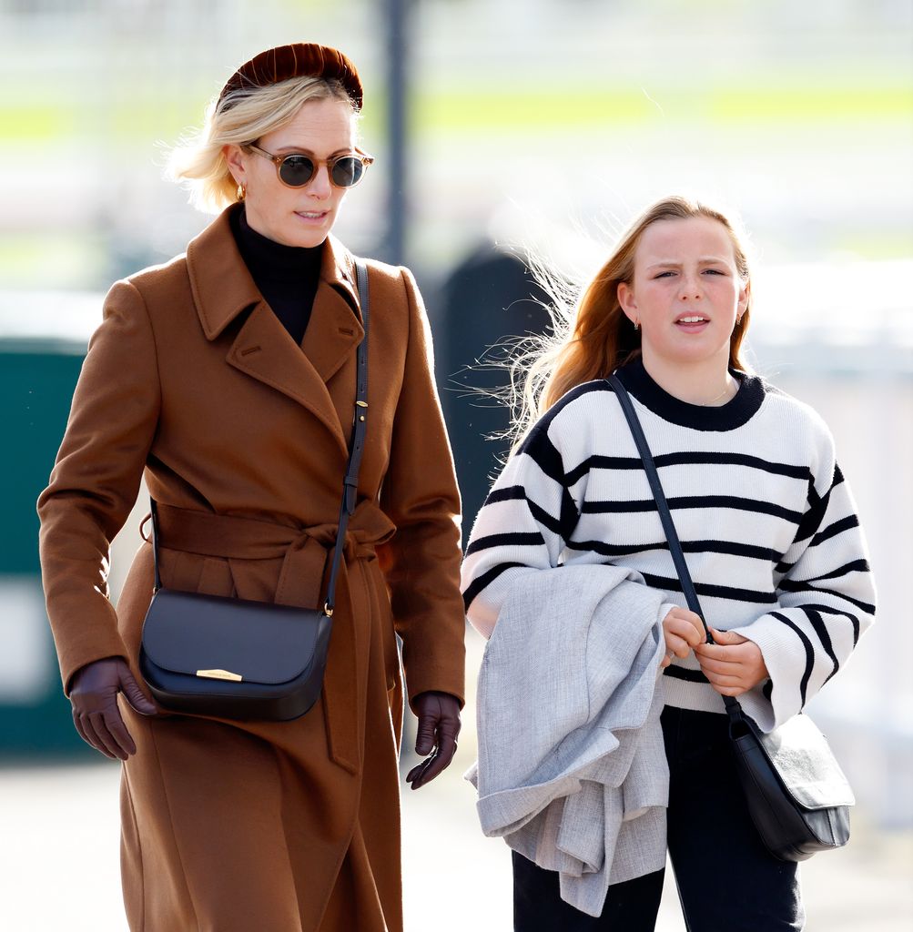 Zara in brown coat and sunglasses beside daughter in striped jumper