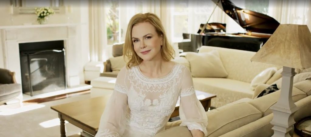 Nicole Kidman in a white dress on a cream sofa in front of a piano