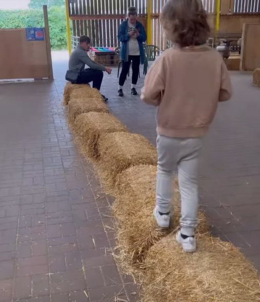 Young boy walking across stacks of hay