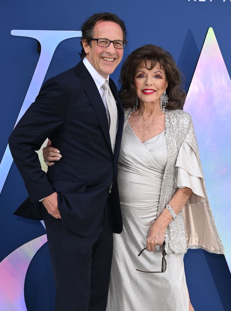 Percy Gibson wearing a black suit with Joan Collins in a silver dress