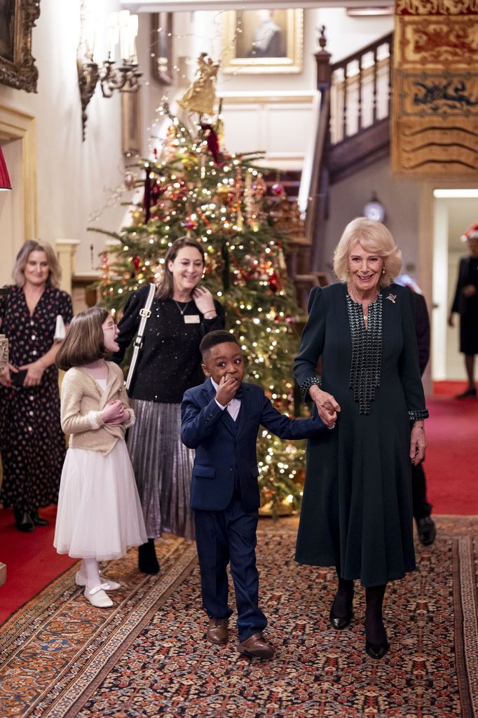 Queen Camilla holds hands with Samuel during the Christmas tree decorating event