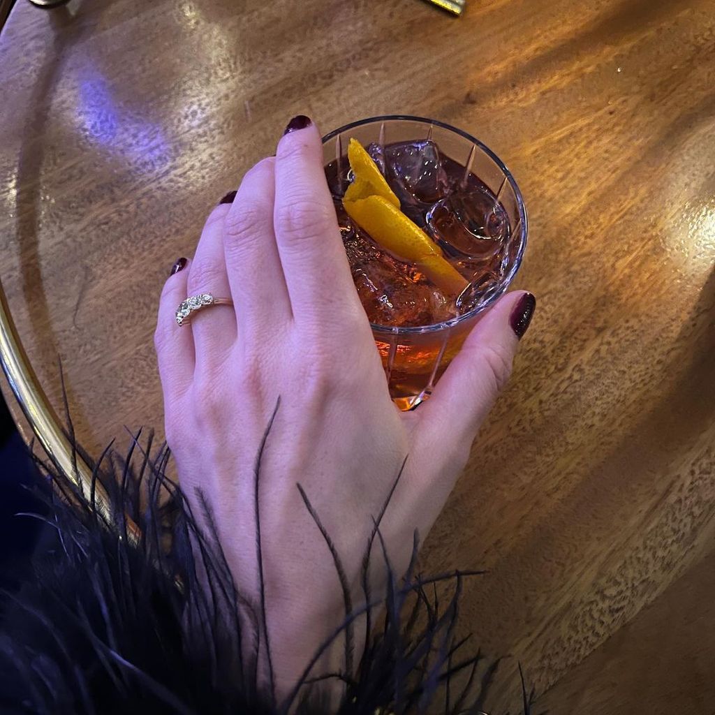 Faye Harris holding a cocktail showing off her engagement ring