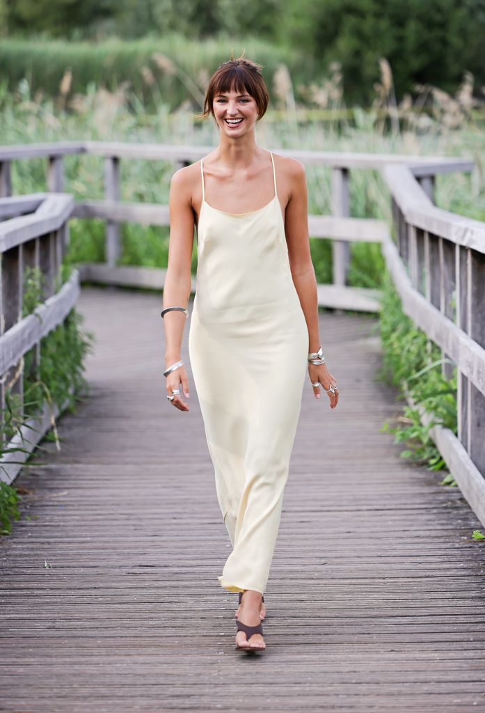 Mia Regan on leafy bridge in pale cream slipdress