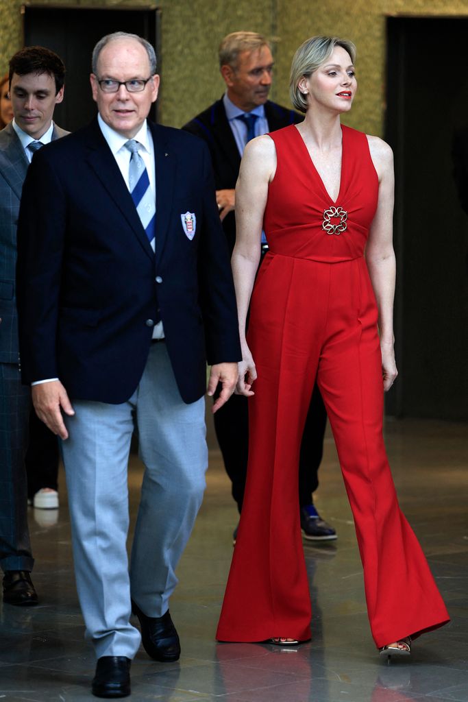 O príncipe Albert e a princesa Charlene em macacão vermelho caminhando