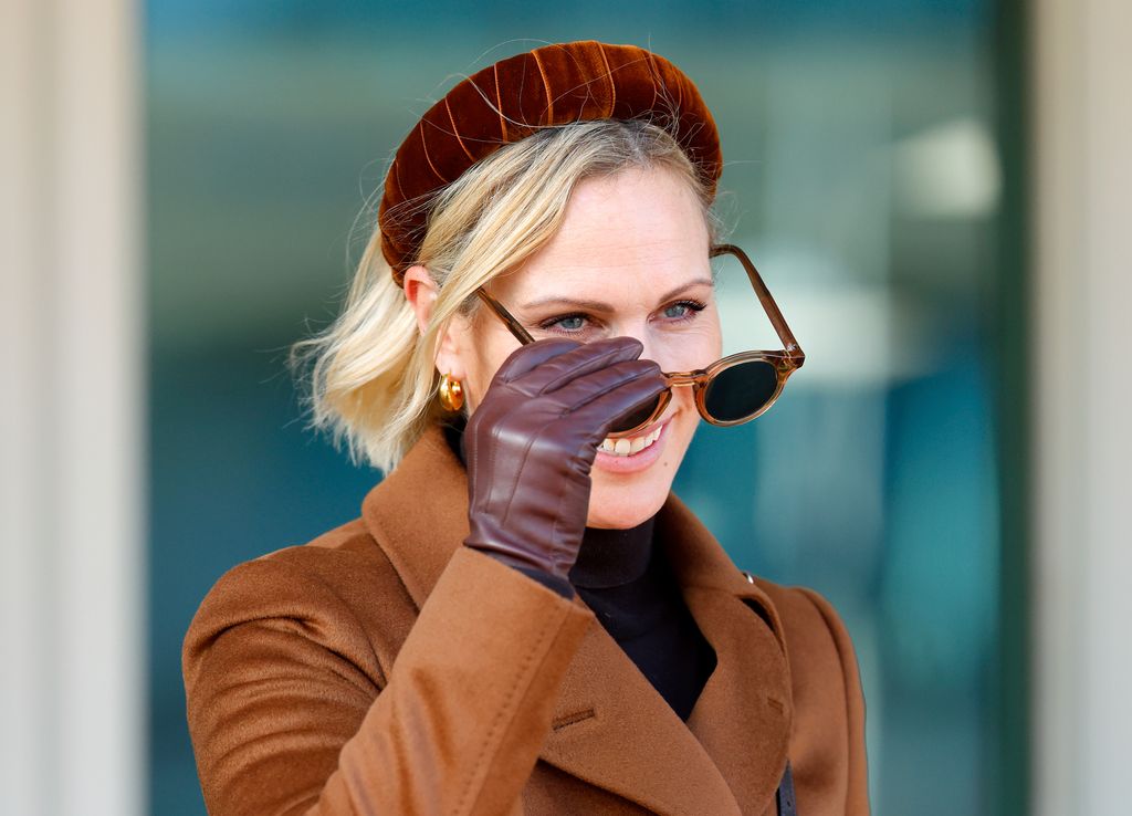 Zara Tindall taking sunglasses off her face in brown coat