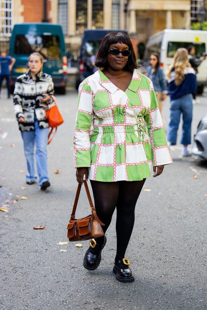 A guest wears green white checkered dress, tights, brown bag outside Ahluwalia during London Fashion Week September 2024 on September 14, 2024 in London, England