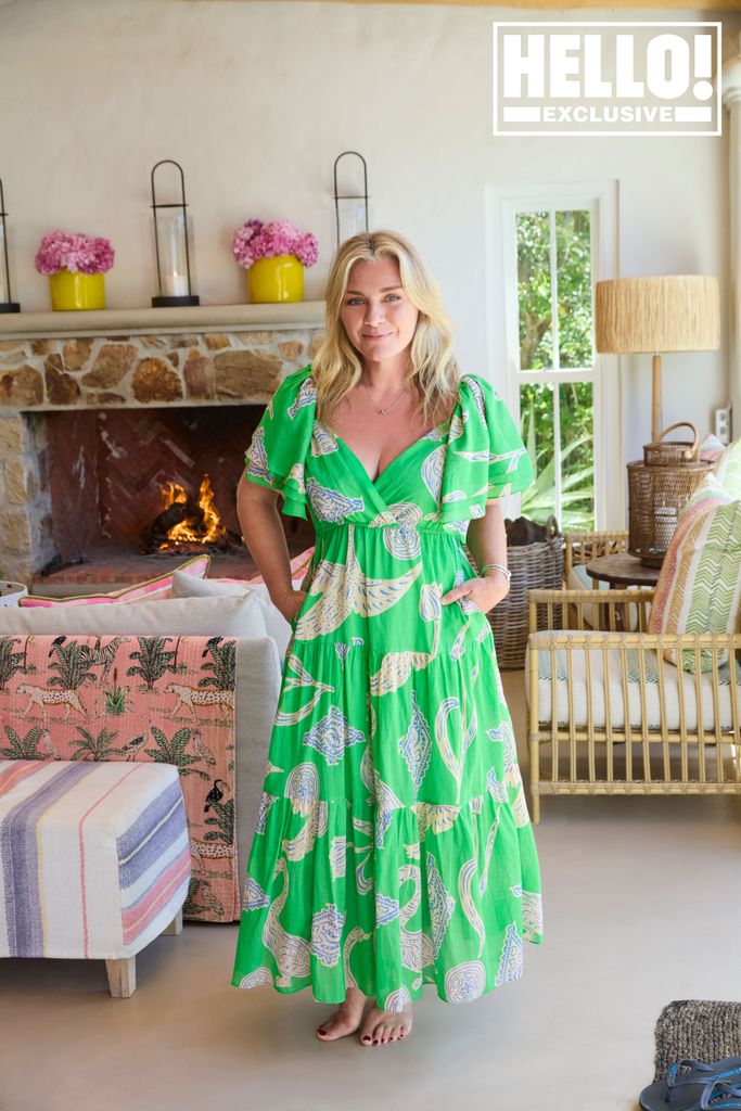 Tabitha Webb in plunging green dress posing in front of fireplace