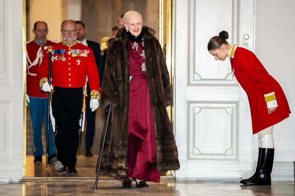 Queen Margrethe wearing a burgundy dress and a furry coat